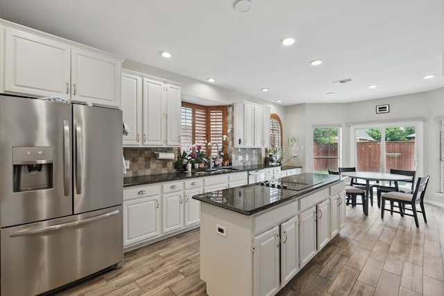 1925 Kiestwood Cir, Plano, TX 75025 - kitchen featuring stainless steel appliances, a center island, light wood finished floors, a sink, and white cabinetry