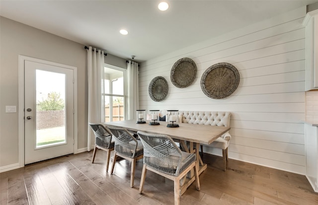 dining space with recessed lighting, wood finished floors, wooden walls, and baseboards