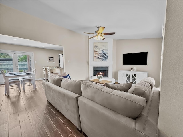 2114 Cottage Oak Ln, Colleyville, TX 76034 - living area with a lit fireplace, ceiling fan, wood finish floors, and baseboards