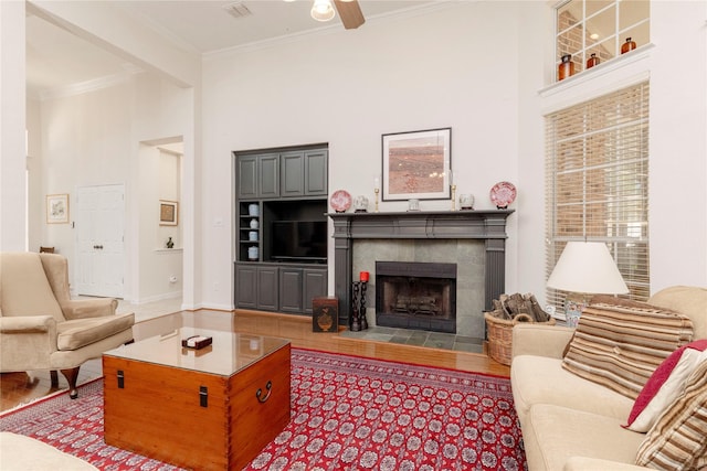 4301 Sandra Lynn Dr, Flower Mound, TX 75022 - living room with a towering ceiling, crown molding, a ceiling fan, a tiled fireplace, and wood finished floors