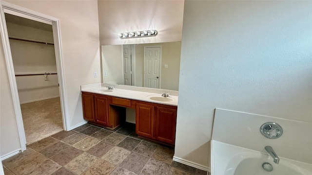 1924 Cliffrose Dr, Little Elm, TX 75068 - bathroom with baseboards, a tub to relax in, double vanity, stone finish flooring, and a spacious closet