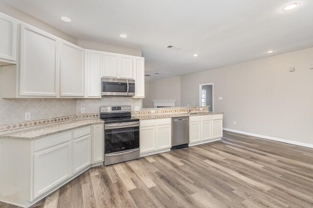 2109 Northridge Dr, Forney, TX 75126 - kitchen with appliances with stainless steel finishes, a peninsula, light wood-style floors, tasteful backsplash, and recessed lighting