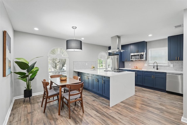 6005 Redwood Ln, Rowlett, TX 75089 - kitchen with stainless steel appliances, island range hood, blue cabinetry, a sink, and recessed lighting