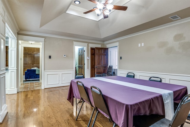 1950 Hidden Vly, Rockwall, TX 75087 - dining room with a tray ceiling, a decorative wall, a ceiling fan, light wood-style floors, and a wainscoted wall