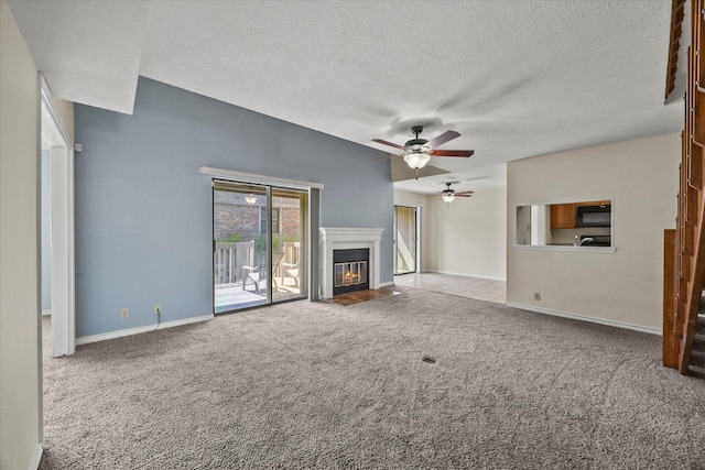 1206 Signal Ridge Pl, Rockwall, TX 75032 - unfurnished living room featuring ceiling fan, carpet floors, a textured ceiling, a fireplace with flush hearth, and baseboards