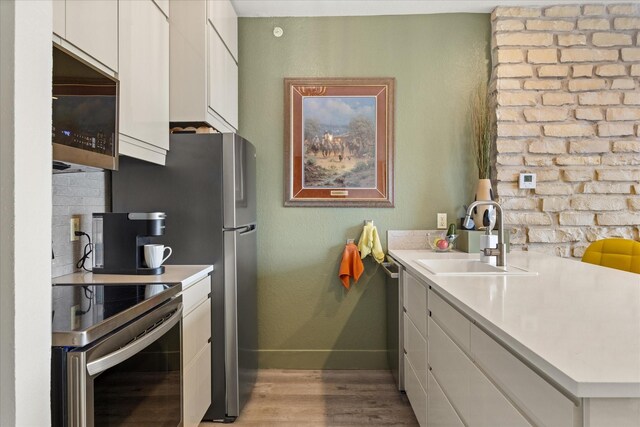401 E Pearl St Unit 2105, Granbury, TX 76048 - kitchen featuring appliances with stainless steel finishes, a sink, light wood-type flooring, and light countertops