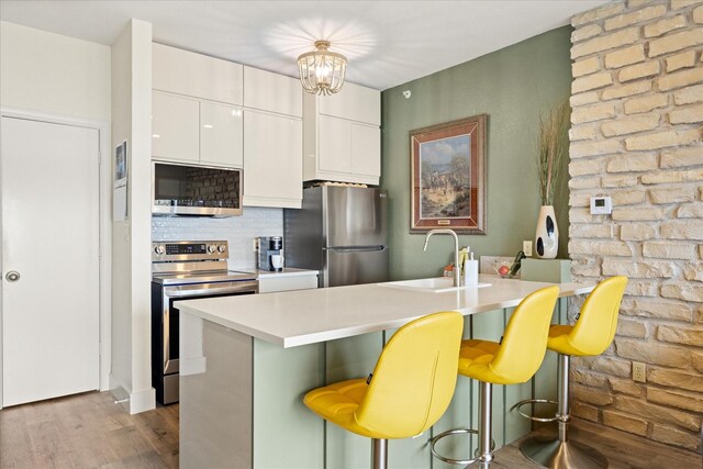 401 E Pearl St Unit 2105, Granbury, TX 76048 - kitchen featuring appliances with stainless steel finishes, a sink, a kitchen bar, dark wood-style flooring, and decorative backsplash