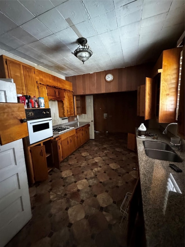 1205 W Arlington Ave, Fort Worth, TX 76110 - kitchen featuring a sink, oven, brown cabinets, dark floors, and gas stovetop