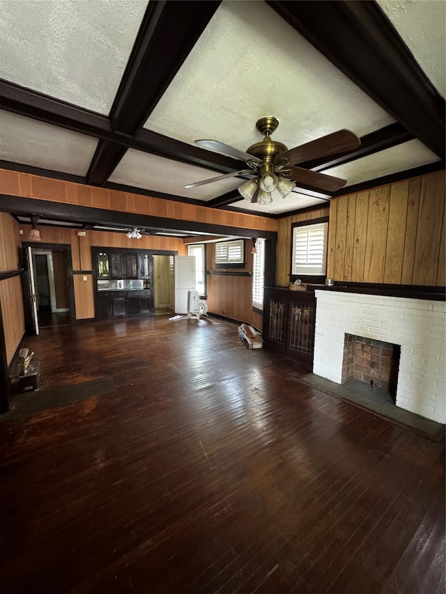 1205 W Arlington Ave, Fort Worth, TX 76110 - unfurnished living room with wooden walls, beam ceiling, a ceiling fan, dark wood-style floors, and a fireplace