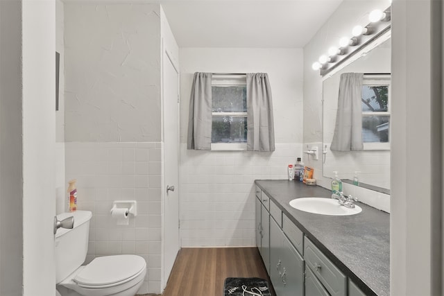 604 S Chestnut St, Winnsboro, TX 75494 - bathroom featuring tile walls, wood finished floors, toilet, vanity, and wainscoting