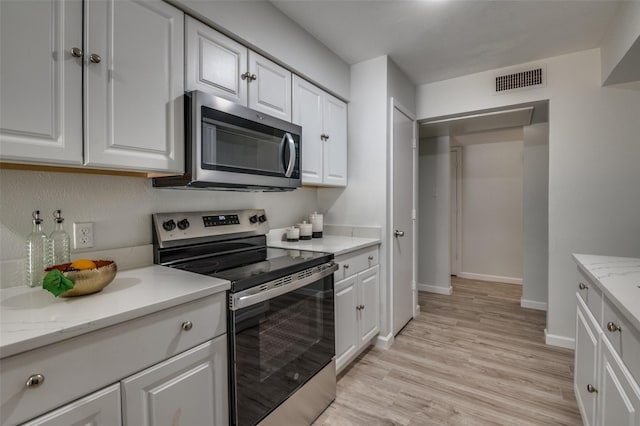 2209 Sheriff Dr, Grand Prairie, TX 75051 - kitchen with appliances with stainless steel finishes, white cabinets, light wood-style floors, baseboards, and light stone countertops