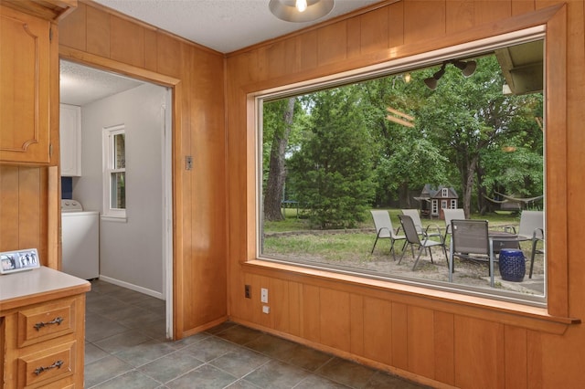 115 Mill Pond Rd, Denton, TX 76209 - dining room featuring washer / clothes dryer, a textured ceiling, healthy amount of natural light, tile patterned flooring, and wooden walls