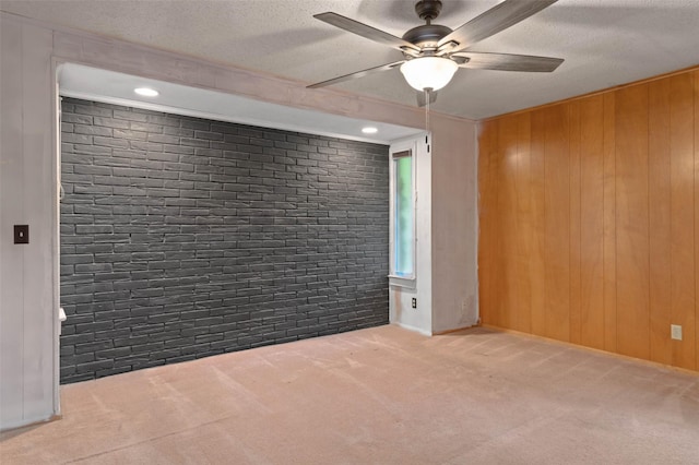 115 Mill Pond Rd, Denton, TX 76209 - spare room featuring carpet flooring, a ceiling fan, brick wall, wooden walls, and a textured ceiling
