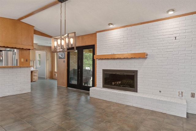 115 Mill Pond Rd, Denton, TX 76209 - unfurnished living room featuring vaulted ceiling, a chandelier, a fireplace, wood walls, and dark tile patterned flooring