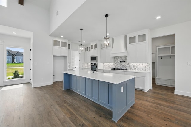 500 Longhorn Dr, Springtown, TX 76082 - kitchen with custom exhaust hood, stainless steel microwave, gas cooktop, white cabinetry, and tasteful backsplash