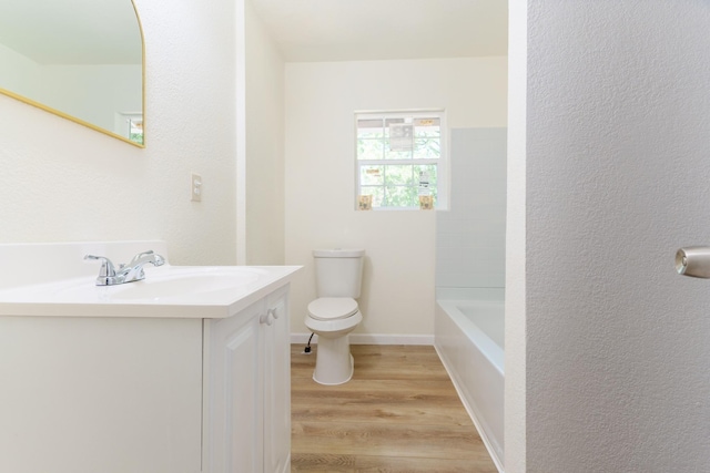 103 N 6th St E, Dawson, TX 76639 - full bathroom with wood finished floors, toilet, vanity, a tub, and a textured wall