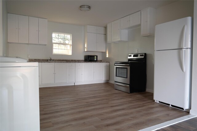 103 N 6th St E, Dawson, TX 76639 - kitchen featuring freestanding refrigerator, stainless steel electric range, black microwave, white cabinets, and light wood finished floors