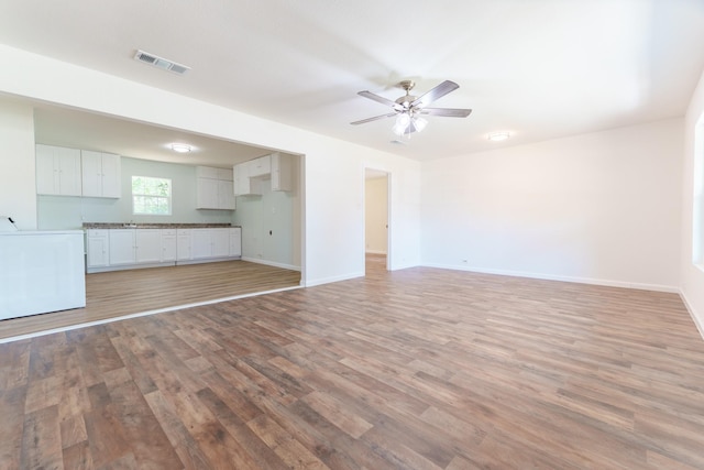 103 N 6th St E, Dawson, TX 76639 - unfurnished living room featuring washer / dryer, light wood-style flooring, baseboards, and a ceiling fan