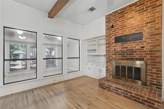 1027 Ridgeview Cir, Carrollton, TX 75007 - unfurnished living room with a fireplace, light wood-style flooring, a ceiling fan, beamed ceiling, and built in features