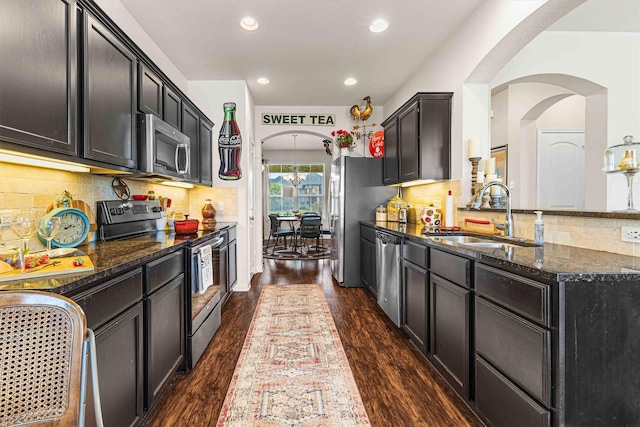 10805 Aurora Dr, Waco, TX 76708 - kitchen featuring stainless steel appliances, a sink, dark stone counters, dark wood-style flooring, and recessed lighting