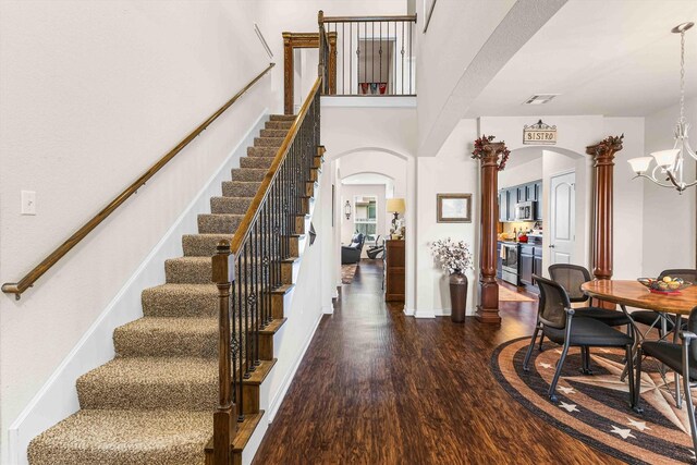 10805 Aurora Dr, Waco, TX 76708 - stairway with arched walkways, wood finished floors, a chandelier, and decorative columns