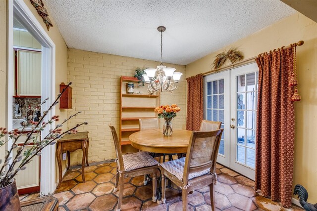 2043 Fleur De Lis Ct, Arlington, TX 76012 - dining space with brick wall, a textured ceiling, a chandelier, and french doors