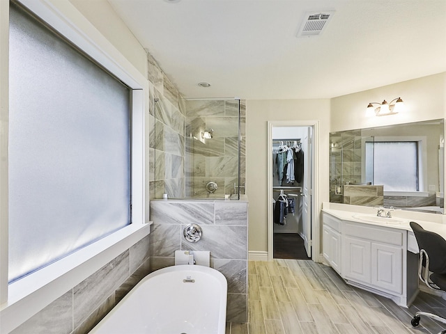 832 Adams Dr, Burleson, TX 76028 - full bathroom featuring a shower stall, a walk in closet, a soaking tub, vanity, and wood finished floors