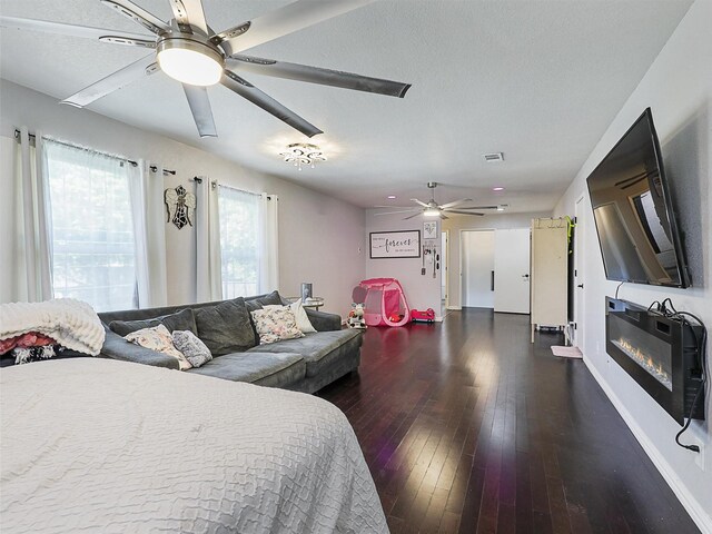 5433 Greenwood Way N, Richland Hills, TX 76180 - bedroom with wood-type flooring, a glass covered fireplace, a ceiling fan, baseboards, and a textured ceiling