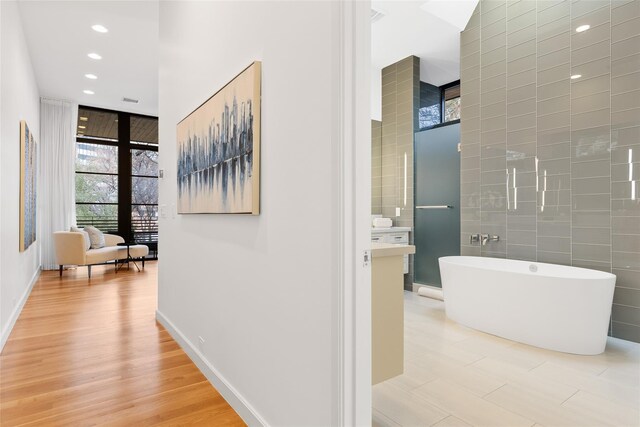 3723 Gilbert Ave, Dallas, TX 75219 - hallway featuring expansive windows, recessed lighting, light wood-style flooring, and baseboards