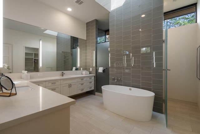 3723 Gilbert Ave, Dallas, TX 75219 - bathroom featuring vanity, tile walls, a freestanding bath, tile patterned flooring, and walk in shower