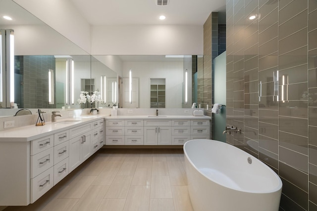 3723 Gilbert Ave, Dallas, TX 75219 - full bathroom with a freestanding bath, double vanity, tile walls, and recessed lighting