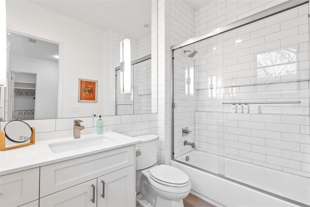 3723 Gilbert Ave, Dallas, TX 75219 - bathroom featuring vanity, combined bath / shower with glass door, toilet, and tile walls
