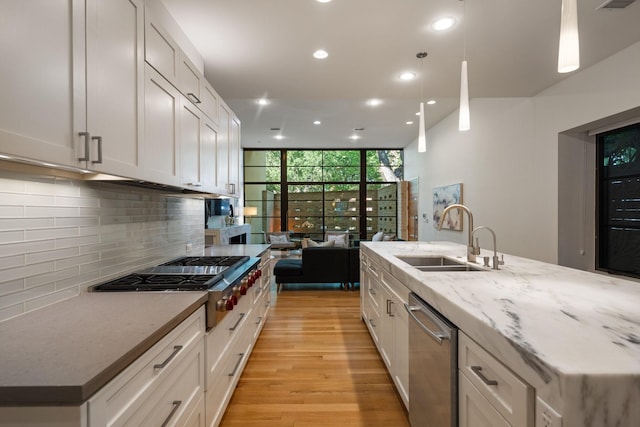 3723 Gilbert Ave, Dallas, TX 75219 - kitchen with a sink, appliances with stainless steel finishes, recessed lighting, tasteful backsplash, and light wood-style flooring