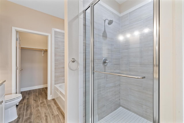 3004 Waterstone Way, Brownwood, TX 76801 - bathroom featuring a shower stall, toilet, wood finished floors, a spacious closet, and a garden tub
