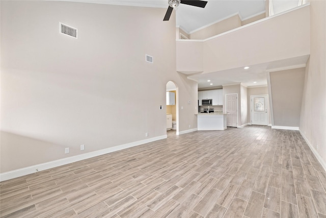 3004 Waterstone Way, Brownwood, TX 76801 - unfurnished living room featuring ceiling fan, baseboards, crown molding, light wood finished floors, and arched walkways