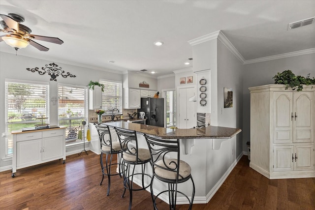 1590 N Hills Dr, Rockwall, TX 75087 - kitchen featuring black refrigerator with ice dispenser, a ceiling fan, dark wood finished floors, a breakfast bar, and recessed lighting