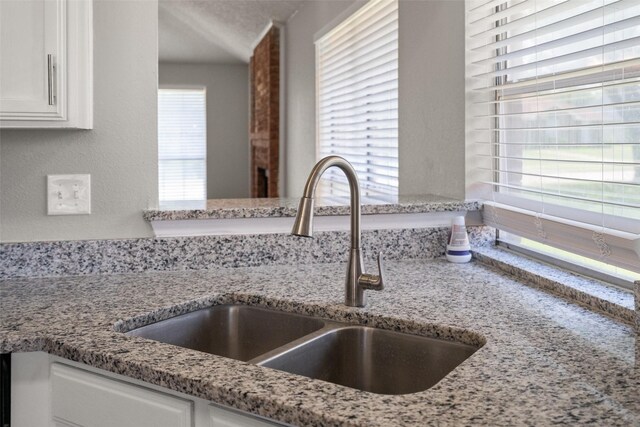 1133 Rosewood Ln, Lancaster, TX 75146 - kitchen view of a sink, white cabinetry, and light stone countertops