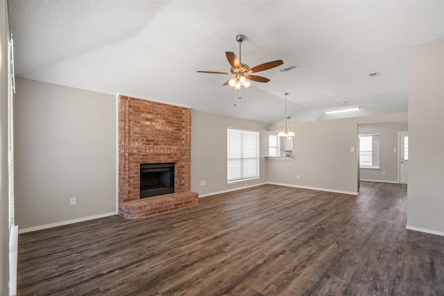 1133 Rosewood Ln, Lancaster, TX 75146 - unfurnished living room featuring vaulted ceiling, a ceiling fan, a brick fireplace, dark wood-type flooring, and baseboards