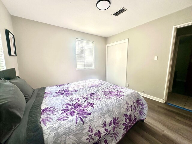 bedroom featuring dark wood-style floors, baseboards, and a closet
