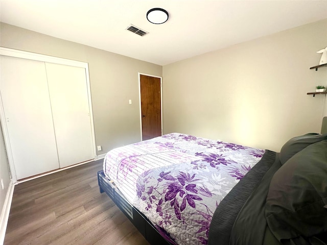 bedroom with wood finished floors, a closet, and baseboards