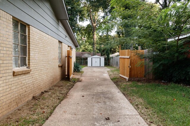 view of yard featuring a storage shed, fence, an outbuilding, and concrete driveway