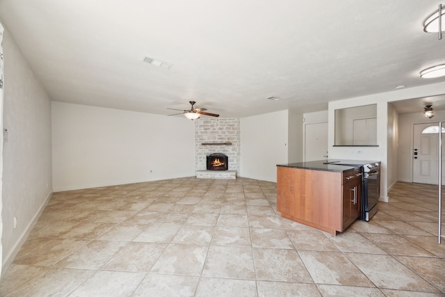kitchen featuring stainless steel electric stove, ceiling fan, a fireplace, open floor plan, and baseboards