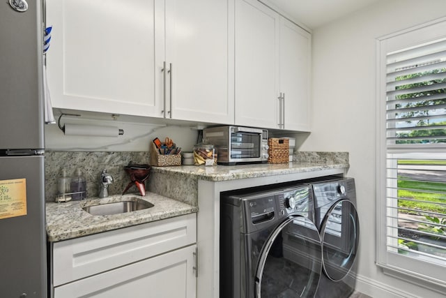 4222 Laren Ln, Dallas, TX 75244 - laundry area with healthy amount of natural light, washer and clothes dryer, and cabinet space
