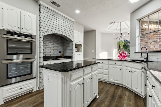 2111 Rheims Dr, Carrollton, TX 75006 - kitchen with stainless steel double oven, a sink, backsplash, a chandelier, and white cabinetry