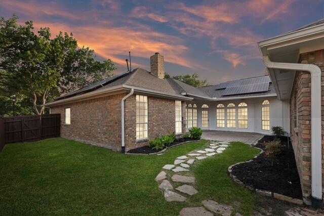 2111 Rheims Dr, Carrollton, TX 75006 - back of house with solar panels, a chimney, brick siding, french doors, and roof with shingles