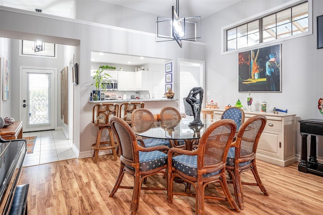 4728 Misty Oak Ln, Arlington, TX 76017 - dining space featuring a chandelier, plenty of natural light, light wood finished floors, and a towering ceiling