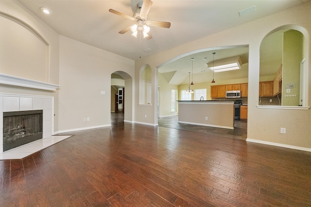 7601 Jennifer Ln, Frisco, TX 75034 - unfurnished living room with ceiling fan, dark wood-style floors, a tiled fireplace, baseboards, and recessed lighting