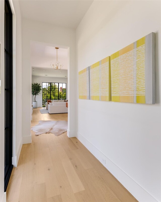 9895 Kingsway Ave, Dallas, TX 75230 - hall featuring a chandelier, light wood-type flooring, and baseboards