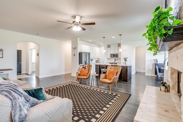 340 Sanger Dr, Springtown, TX 76082 - living room featuring arched walkways, ceiling fan, dark wood-style flooring, baseboards, and ornamental molding