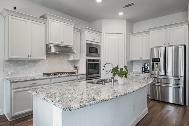 5542 Yellowstone Rd, The Colony, TX 75056 - kitchen with stainless steel appliances, under cabinet range hood, a sink, dark wood-style floors, and a center island with sink